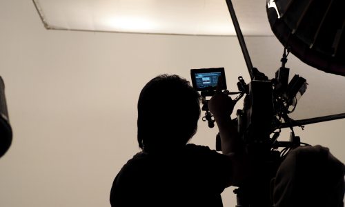 Silhouette of photographer checking for movie camera and set before shooting in studio.